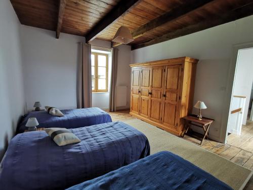 1 dormitorio con 2 camas y armario de madera en La Vallée, en Saint-Pierre-Langers