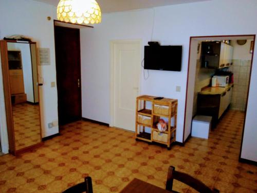 a living room with a table and a tv on a wall at Casa La Quiete in Orco Feglino
