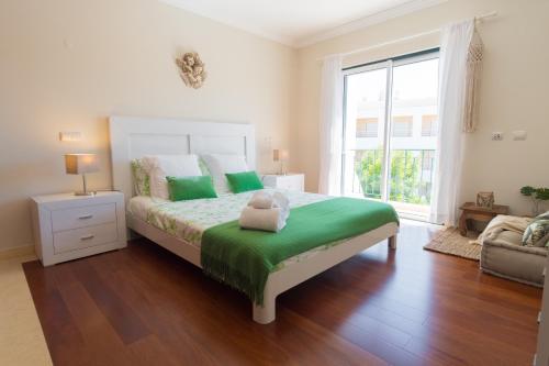 Un dormitorio con una cama con sábanas verdes y una ventana en Villa Ria Rose, Alto da Ria 23 - jacuzzi and beach, en Alvor