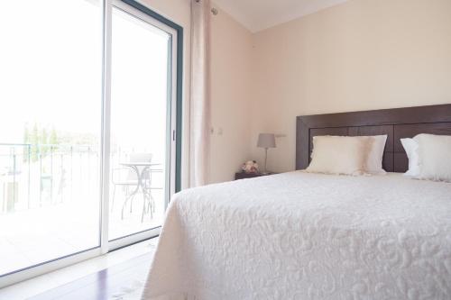 a white bedroom with a bed and a large window at Villa Ria Rose, Alto da Ria 23 - jacuzzi and beach in Alvor