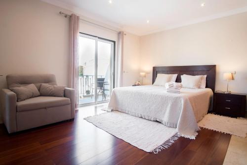 a bedroom with a bed and a couch and a window at Villa Ria Rose, Alto da Ria 23 - jacuzzi and beach in Alvor