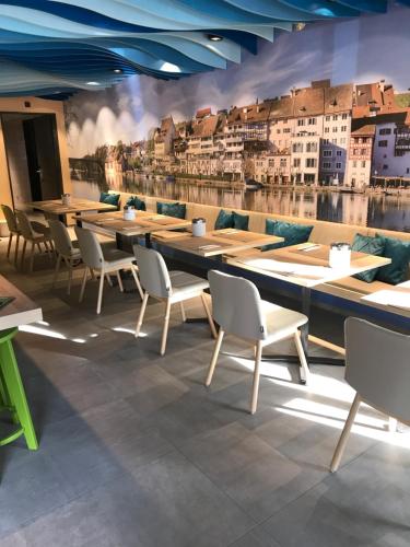 a restaurant with tables and chairs and a wall with buildings at Hotel sleep&stay - Self Check-in in Eglisau
