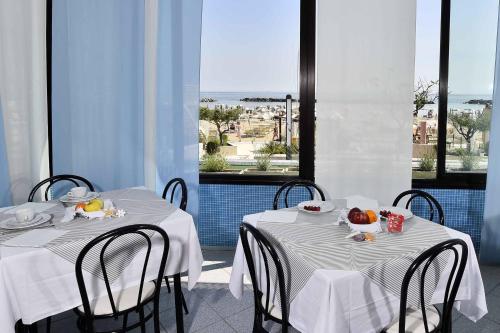 dos mesas con manteles blancos y frutas. en Hotel Admiral en Bellaria-Igea Marina