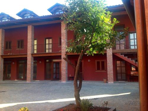 un bâtiment rouge avec un arbre devant lui dans l'établissement Tenuta Roletto, à Cuceglio