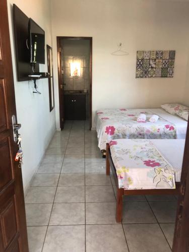 a room with two beds and a television in it at Pousada do Holandês in Canoa Quebrada
