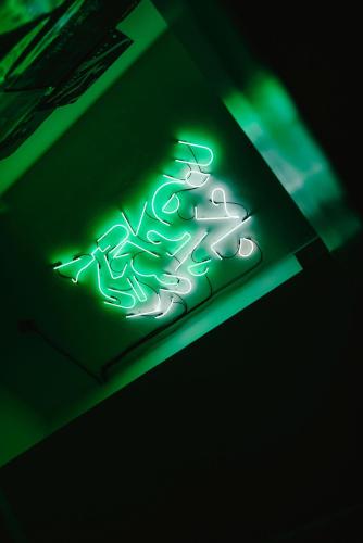 a green neon sign on top of a ceiling at Wake Up Wellness Hostel in Brno