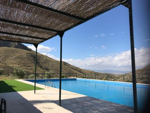 uma grande piscina com telhado de palha em Cortijo El Rancho em Albánchez