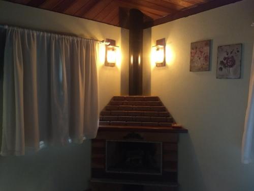 a room with a fireplace and two lights on the wall at Chalé dois irmãos in Visconde De Maua