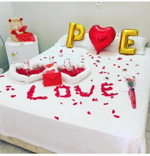 a white bed with red hearts and the words love at Pousada do Holandês in Canoa Quebrada