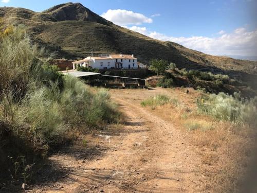 uma estrada de terra com uma casa no lado de uma colina em Cortijo El Rancho em Albánchez