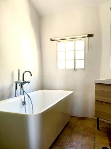 une baignoire dans une salle de bain avec une fenêtre dans l'établissement la bonbonniere - Townhouse Saint-Saturnin-lès-Apt, à Saint-Saturnin-lès-Apt