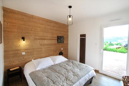 1 dormitorio con una pared de madera y 1 cama en Le Balcon des Lumières, en Gérardmer