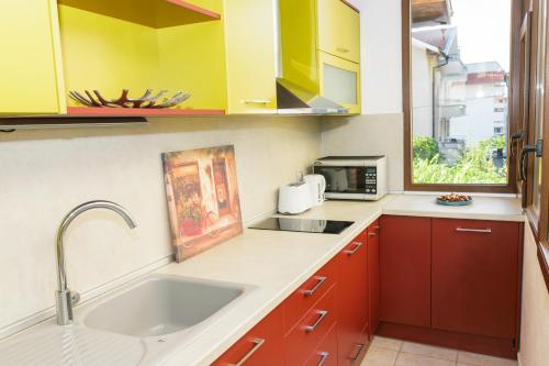 チェルノモレツにあるHoliday house Gendar, Chernomoretsの赤と黄色のキャビネットとシンク付きのキッチン