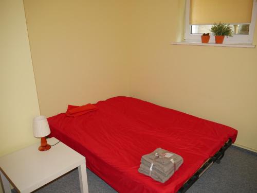 een rood bed in een kamer met een tafel en een raam bij Apartament w centrum Gdyni in Gdynia