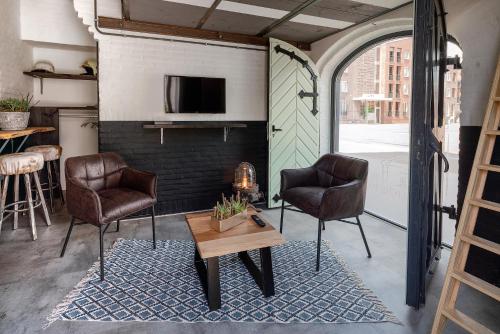 een woonkamer met 2 stoelen en een tafel bij De Oude Kazerne Torenkamer in Kaatsheuvel