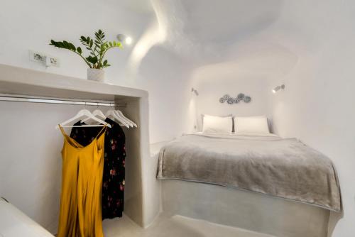 a bedroom with a bed and a yellow dress on a rack at Antrum Cave Villa in Imerovigli