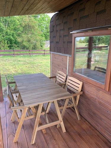 una mesa de picnic de madera y sillas en un porche en Labrags Saulrieti en Jūrkalne