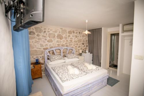 - une chambre avec un lit et un mur en pierre dans l'établissement Rooms Epidaurus, à Dubrovnik