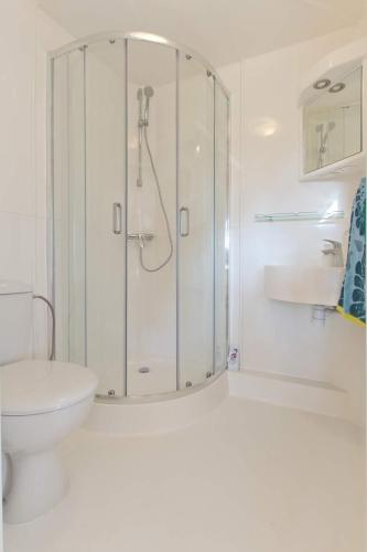 a white bathroom with a shower and a toilet at Domki Reston in Jastrzębia Góra