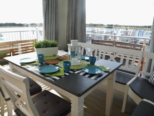 een eettafel en stoelen met uitzicht op een boot bij Schleikieker Maisonette in Olpenitz