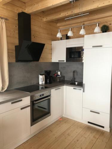 a kitchen with white appliances and wooden walls at Stubihuettn in Sonnenalpe Nassfeld