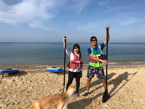 a man and a woman and a dog on the beach at Tom and Rimi's in Kumejima