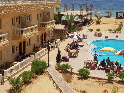 a view of a resort with a pool and people sitting at Ciao Hotel in Nuweiba