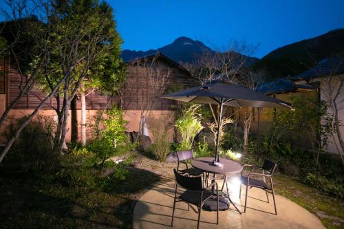 a table and chairs with an umbrella in a yard at Oyado Ichizen in Yufuin
