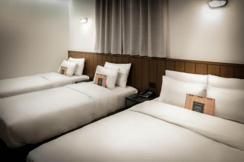 two beds in a hotel room with white pillows at Hotel Lumia Myeongdong in Seoul