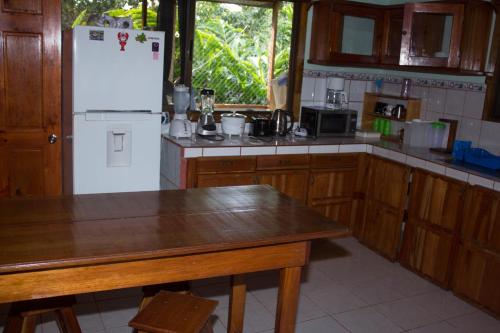 a kitchen with a white refrigerator and wooden cabinets at CasitaCecropia Rental in Drake