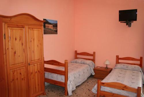 una camera con due letti e una TV a parete di Casa Vacanze Margherita a Locogrande