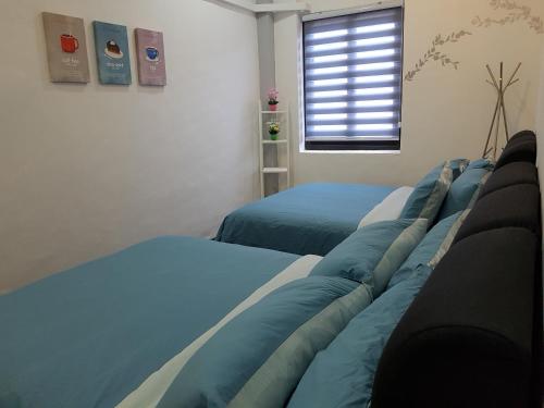 a bedroom with two blue beds and a window at Home@KKB in Kuala Kubu Baharu