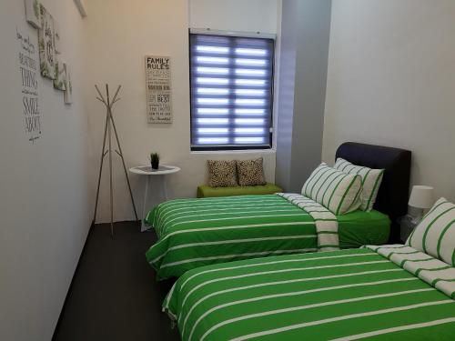 two beds in a room with green and white stripes at Home@KKB in Kuala Kubu Baharu