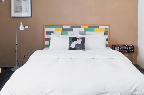 a bedroom with a white bed with a colorful headboard at Lai Jia I 鄰近花園夜市 in Tainan