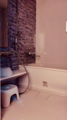 a bathroom with a bath tub with a hose at NAOUMI HOUSE in Kanazawa