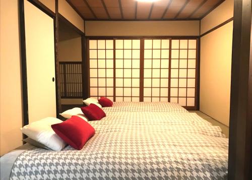 a bedroom with a bed with red and white pillows at NAOUMI HOUSE in Kanazawa