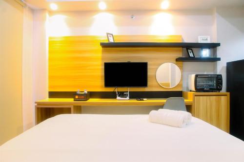 a bedroom with a bed and a desk with a television at Comfy Studio Apartment No Kitchen Mustika Golf Residence By Travelio in Pegadungan