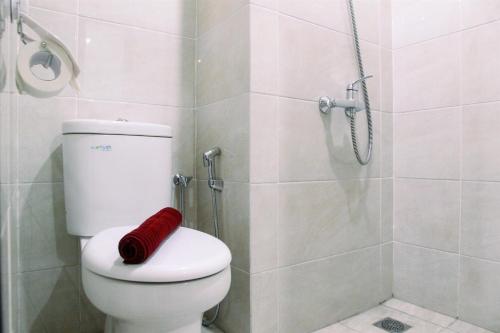 a bathroom with a shower and a toilet with a red towel at Comfy Studio Apartment No Kitchen Mustika Golf Residence By Travelio in Pegadungan