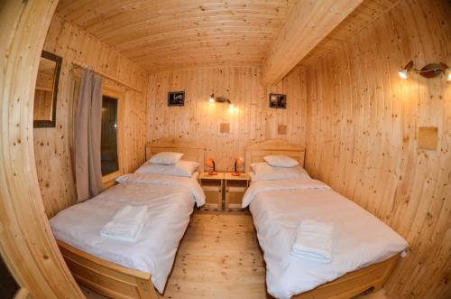 a room with two beds in a wooden cabin at Malom Apartman 2 in Derekegyház