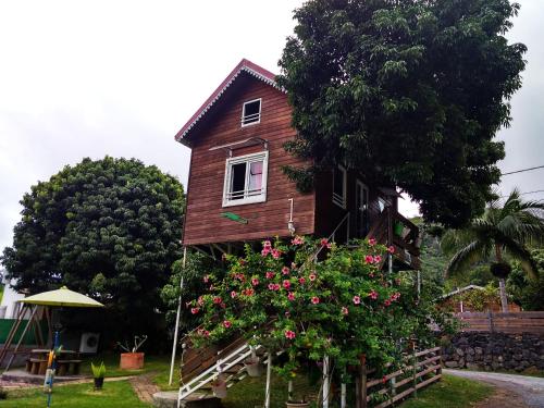 a wooden house with flowers in front of it at ti kaz perchée in LʼEntre-Deux