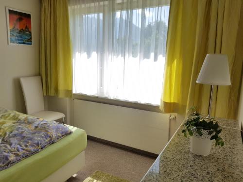 a bedroom with a bed and a window with yellow curtains at DreamlandRanch Vorarlberg in Schlins