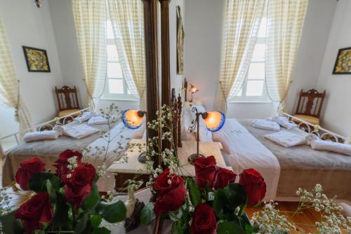 um quarto com duas camas com rosas vermelhas no primeiro plano em Hydra's Pearl - Gold Pearl em Hidra