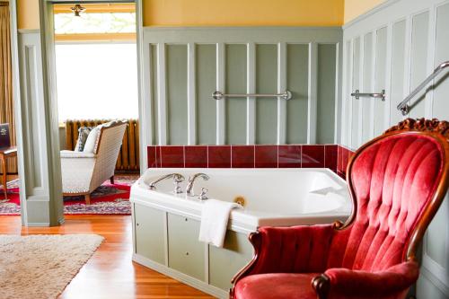 ein Badezimmer mit einer Badewanne und einem roten Stuhl in der Unterkunft Dashwood Manor Seaside Bed & Breakfast in Victoria