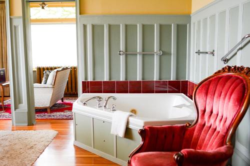 a bath room with a tub and a chair in it at Dashwood Manor Seaside Bed & Breakfast in Victoria