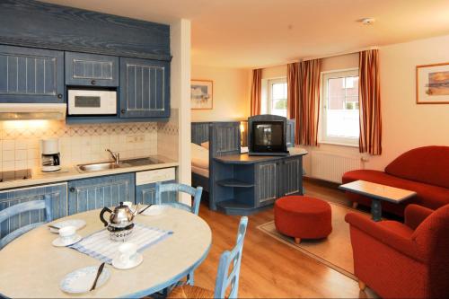 a kitchen and living room with a table and a couch at Hotel Strandhof in Baltrum