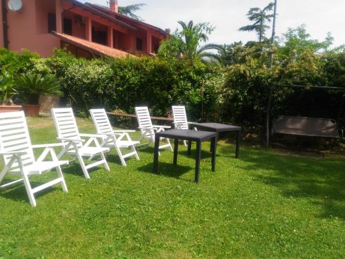 a group of white chairs and a table in the grass at Agriturismo La Quiete in Roncofreddo