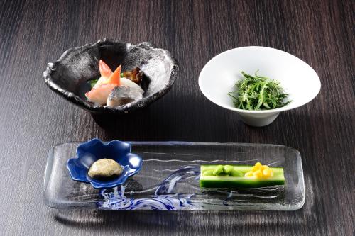 a table with a plate of food and a bowl of vegetables at Akari no Yado Okabe in Shibukawa