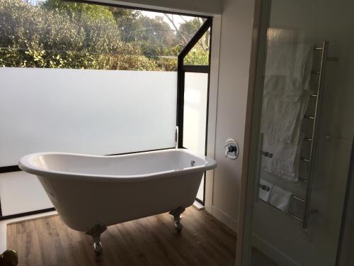 a white bath tub in a bathroom with a window at Chris's Cabin in Greytown