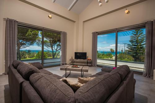 a living room with a large couch and large windows at Vizantida Maisonette, By TK Property Management in Zakynthos Town