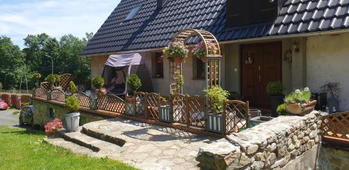 una casa con porche con sillas y plantas en Zagroda AlpakoTerapii, en Świeradów-Zdrój